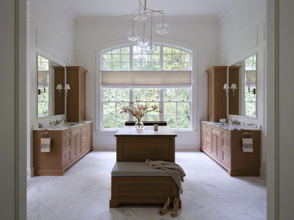 Luxury bathroom with symmetrical custom wood vanities, marble countertops, matching storage cabinetry, and a furniture-style center island by Unique Kitchens & Baths™.