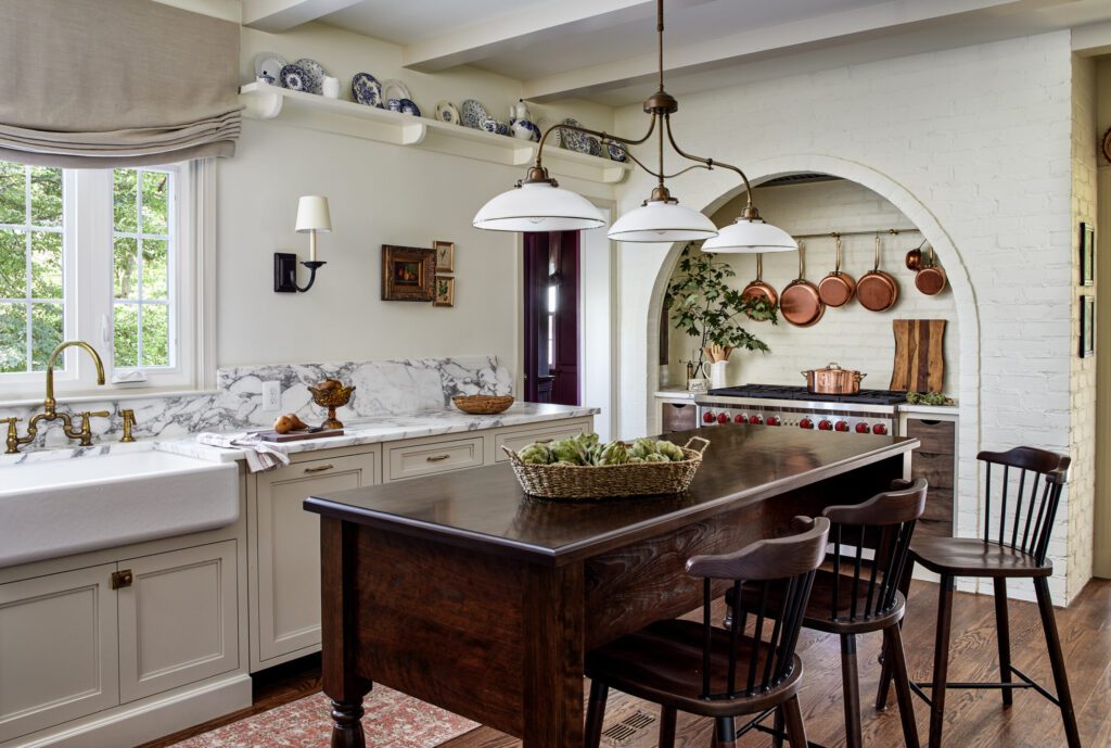 Traditional kitchen with custom cream cabinetry, dark wood island, marble countertops, and thoughtful kitchen lighting by Unique Kitchens & Baths™.